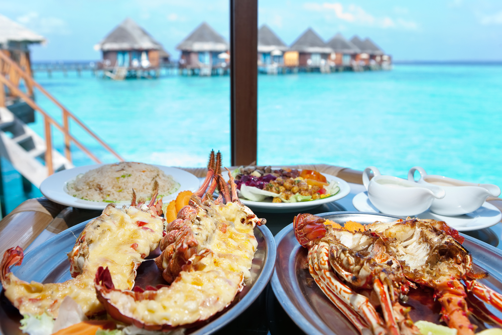 Two plates with lobster on table with view over the ocean in Maldives