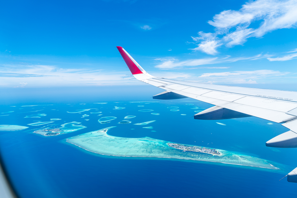 Maldives islands top view from airplane window with airplane's wing