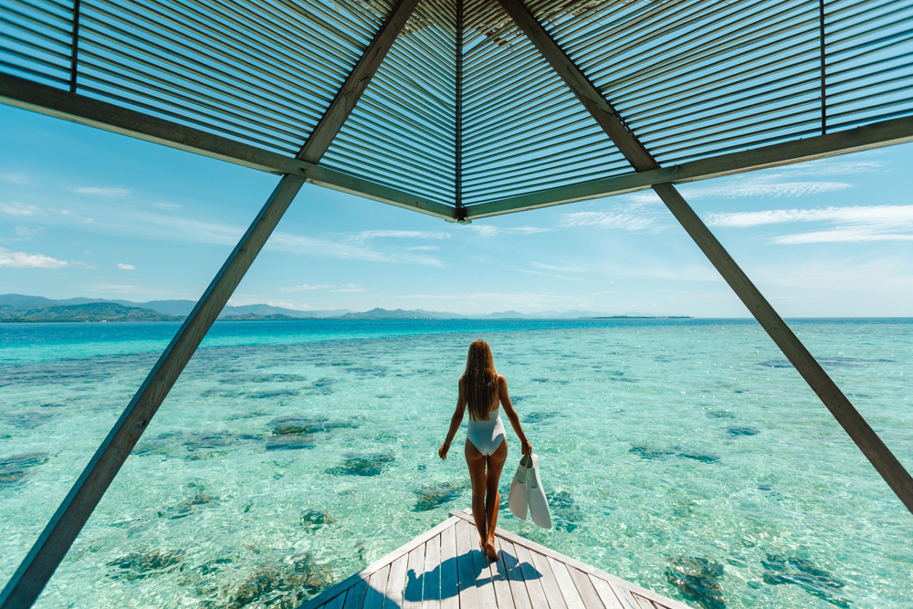 Private luxury overwater bungalows in Maldives resort with a woman going snorkeling