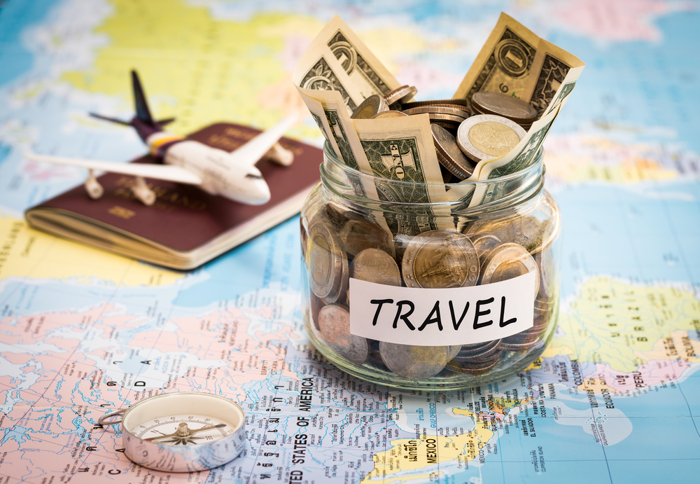 Travel budget concept. Travel money savings in a glass jar with comp