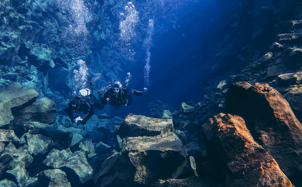 Snorkelers and scuba divers swimming in famous popular Silfra fissure