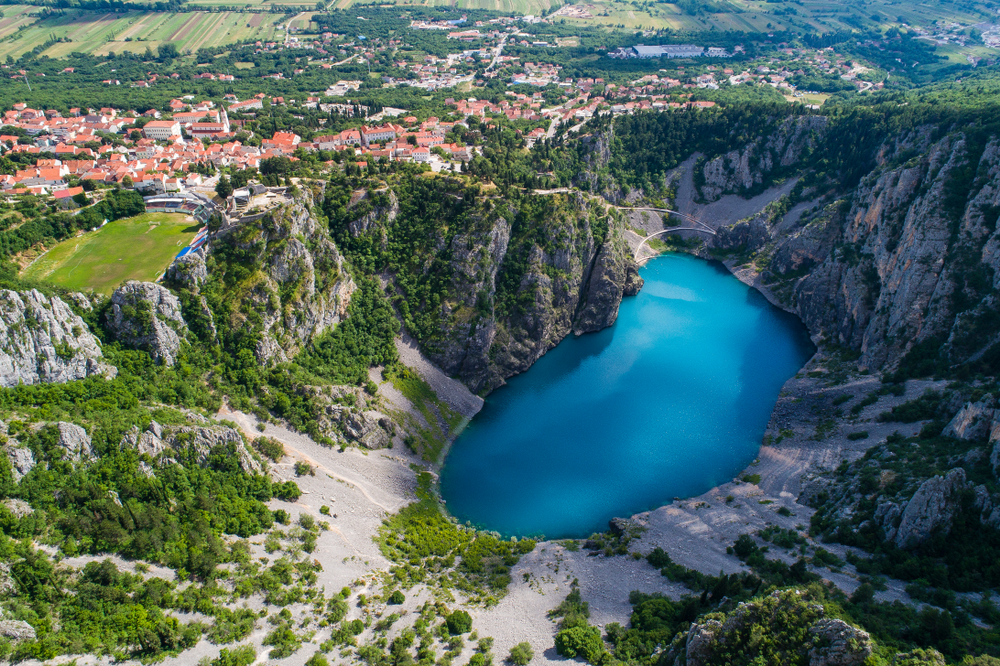 Beautiful nature and landscape photo of Blue Lake in Imotski Dalmatia Croatia on warm summer day. Nice colorful image of mountains and lake shot with drone from above.