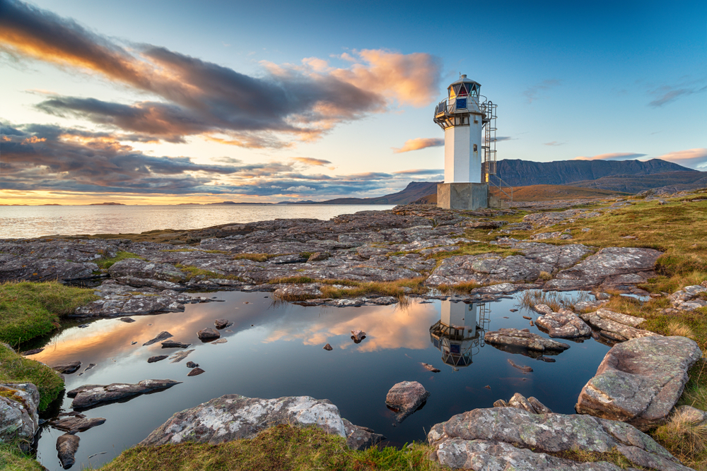 Sunset over Rhue Lighthouse reflected in a rock pool near Ullapool in the Highlands of Scotland