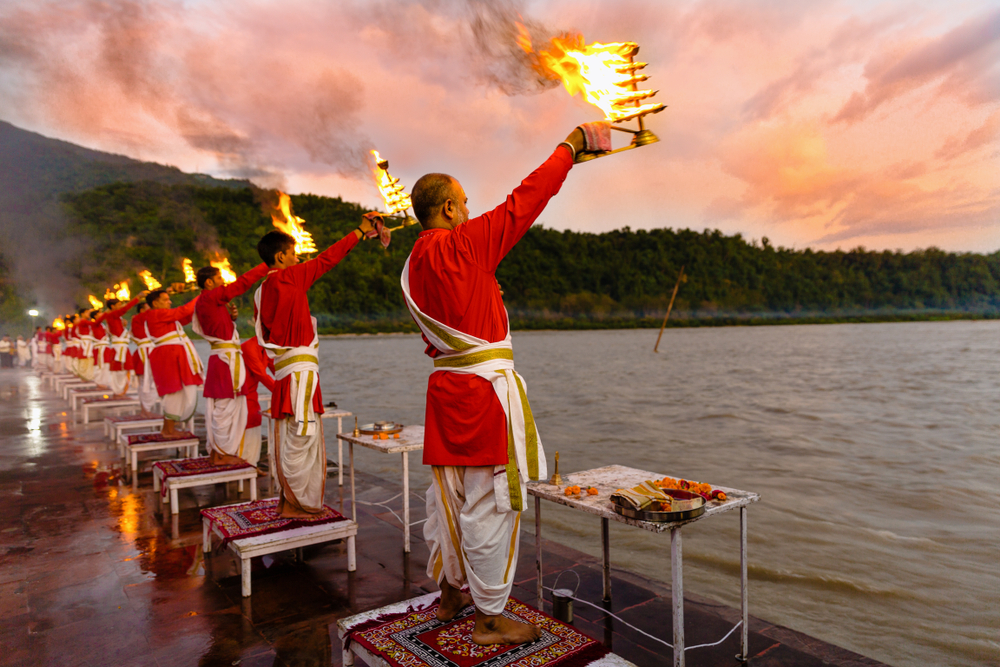 Priests in red robe in the holy city of Rishikesh in Uttarakhand, India during the evening light ceremony called Ganga arthi to worship river Ganga / Ganges.