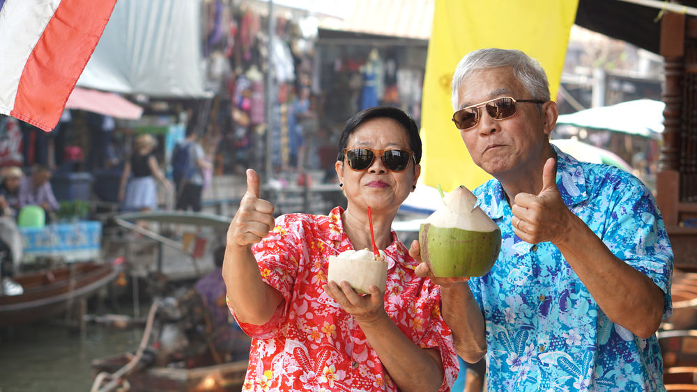 Asian senior elder couple drinking coconut juice at floating market. Travel to Thailand