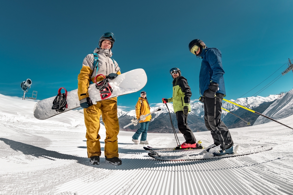 Group of tourists skiers and snowboarders stands at ski resort. Winter sports concept