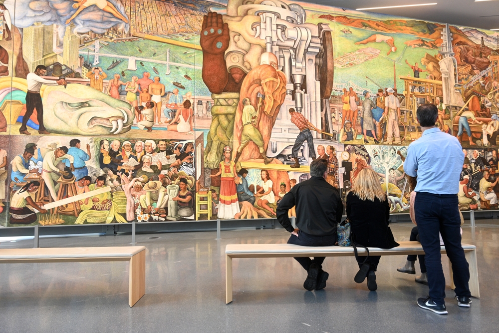 People observing "Pan American Unity" a mural painted by Mexican artist Diego Rivera in San Francisco Museum of Modern Art