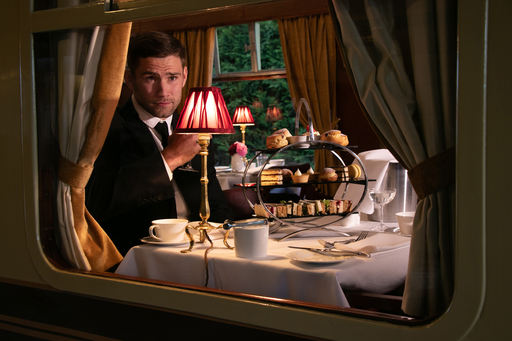 male wearing suit enjoying afternoon tea in train carriage