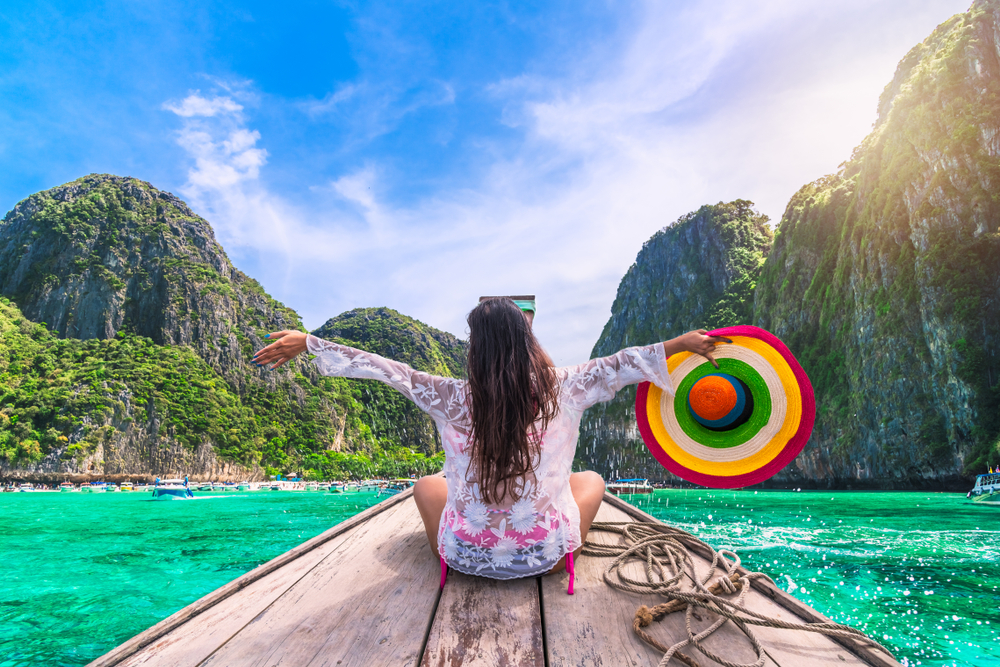 Happy traveler woman in summer dress joy fun relaxing on boat, Maya beach, Phi Phi island, Tourism Phuket