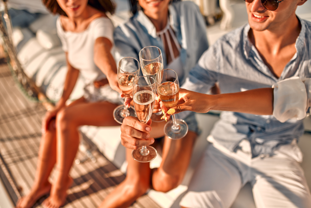 Cropped image of group of friends relaxing on luxury yacht and drinking champagne.