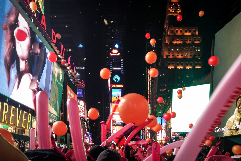 The Times Square New Year's Eve celebration famous for Ball Drop. Balloons falling from the sky and cheering crowds with balloon sticks.
