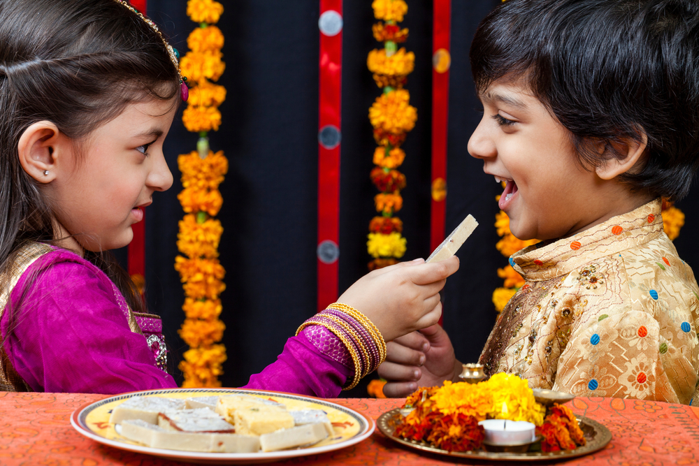 New Delhi, October 20, 2012: Cute Indian siblings celebrate the auspicious festival of Diwali, Sweet girl offers sweets to her brother