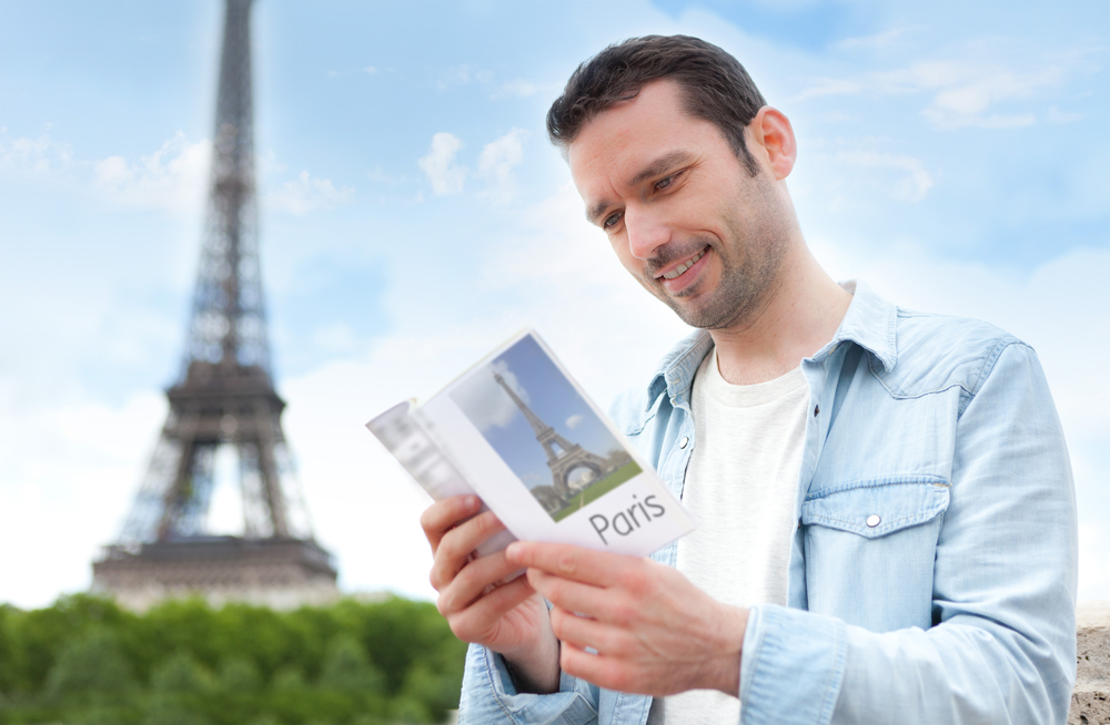 View of a Young attractive tourist reading a guide in Paris , France