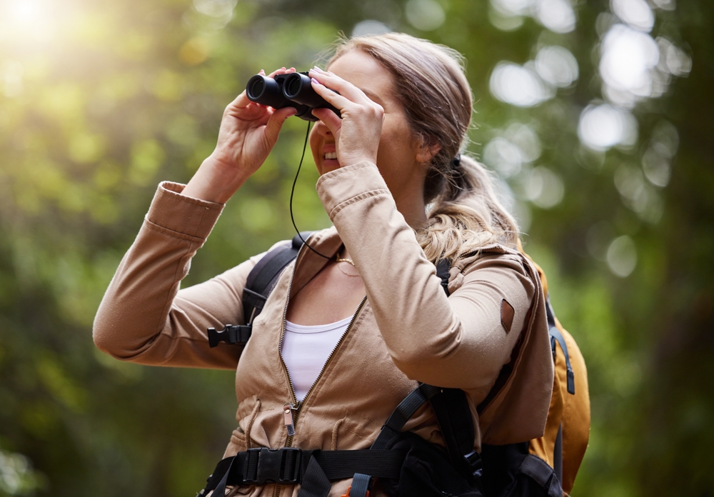 Binoculars, forest explore and woman on travel journey, jungle adventure or hiking for carbon footprint holiday. 