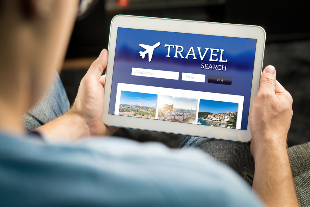 Man searching cheap flights, hotel or holiday package on internet by using online travel search application with tablet.