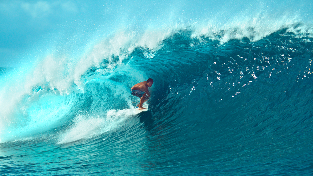 Young pro surfer surfs a big barrel wave in popular surf spot in breathtaking Tahiti.