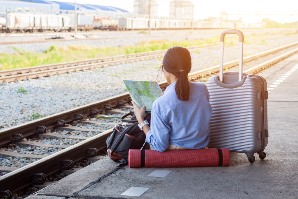 Young woman backpacker at the train station and looking on the map for plan to travel