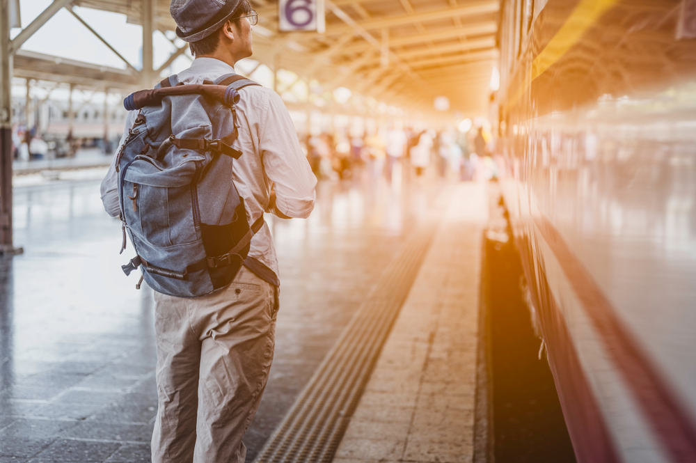 Young man traveling backpacker in train station.travel concept.