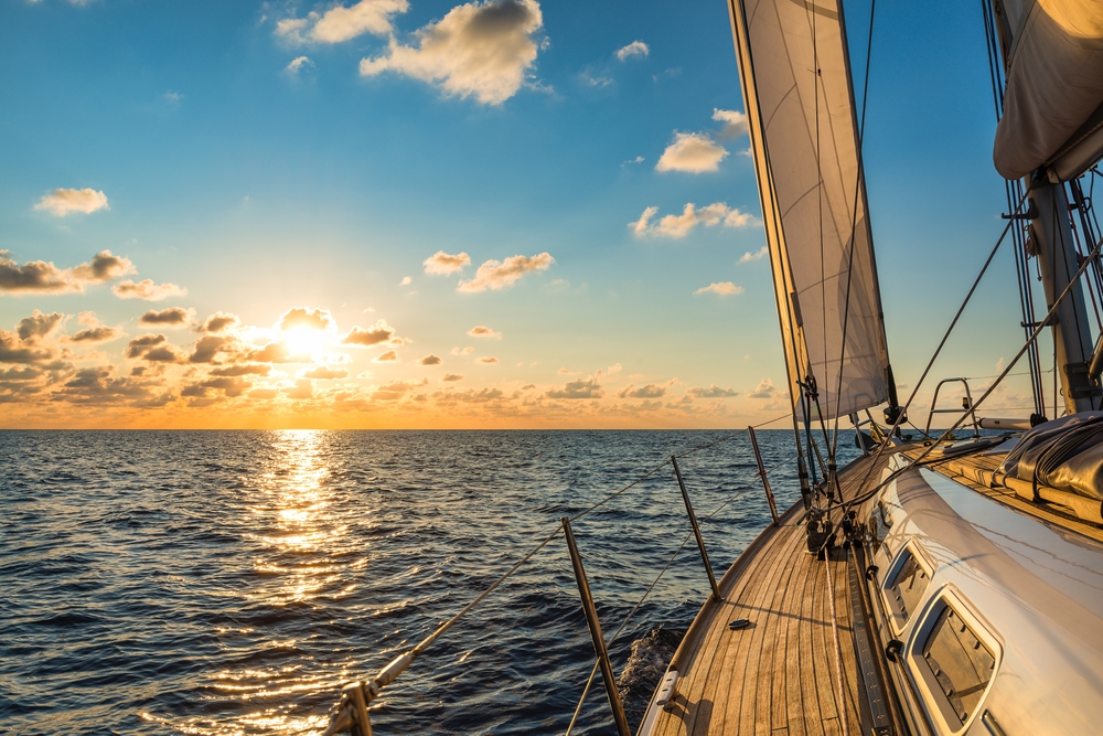 Cruising sailboat sailing in the Mediterranean Sea at sunset