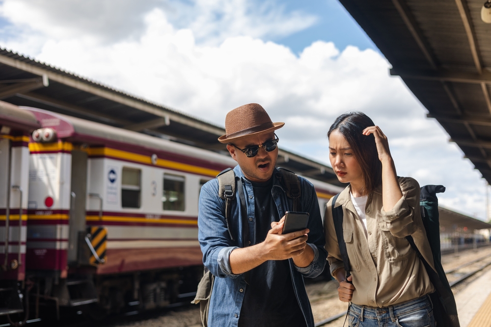 Couple Asian depressed mistakes a train. Two backpacker Traveler waiting at train station.