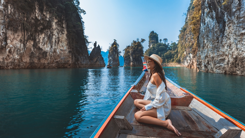 Travel summer vacation concept, Happy solo traveler asian woman with hat relax and sightseeing on Thai longtail boat