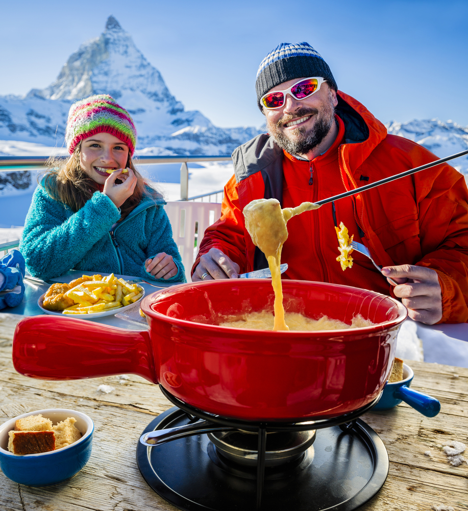 Ski lunch in a restaurant, Fondue, traditional Swiss Alps dish - Matterhorn in background