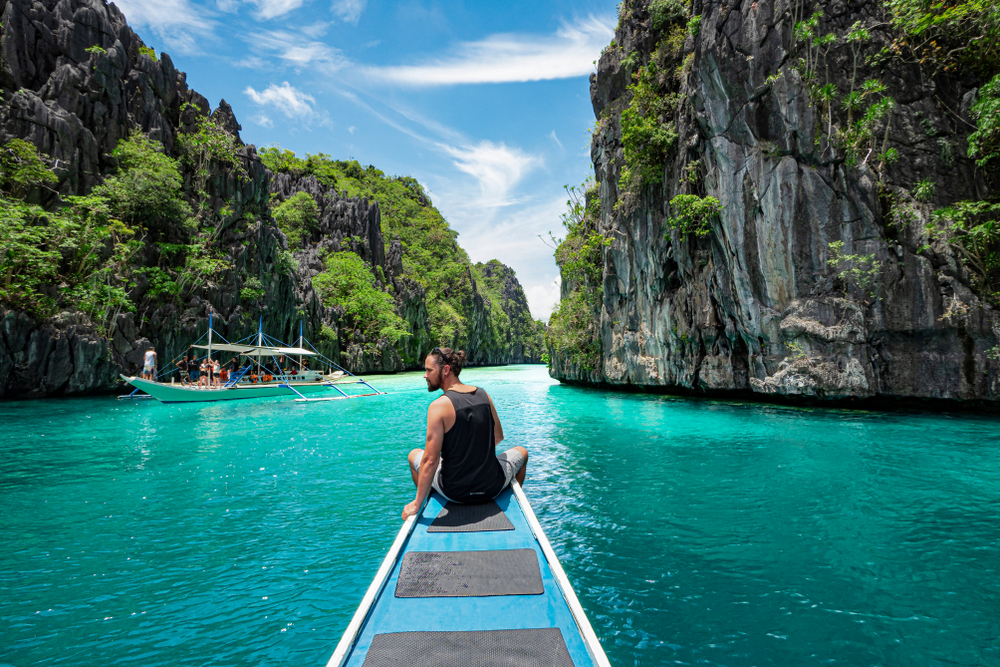 El Nido, Palawan, Philippines, traveler sitting on boat deck exploring the natural sights around El Nido on a sunny day.