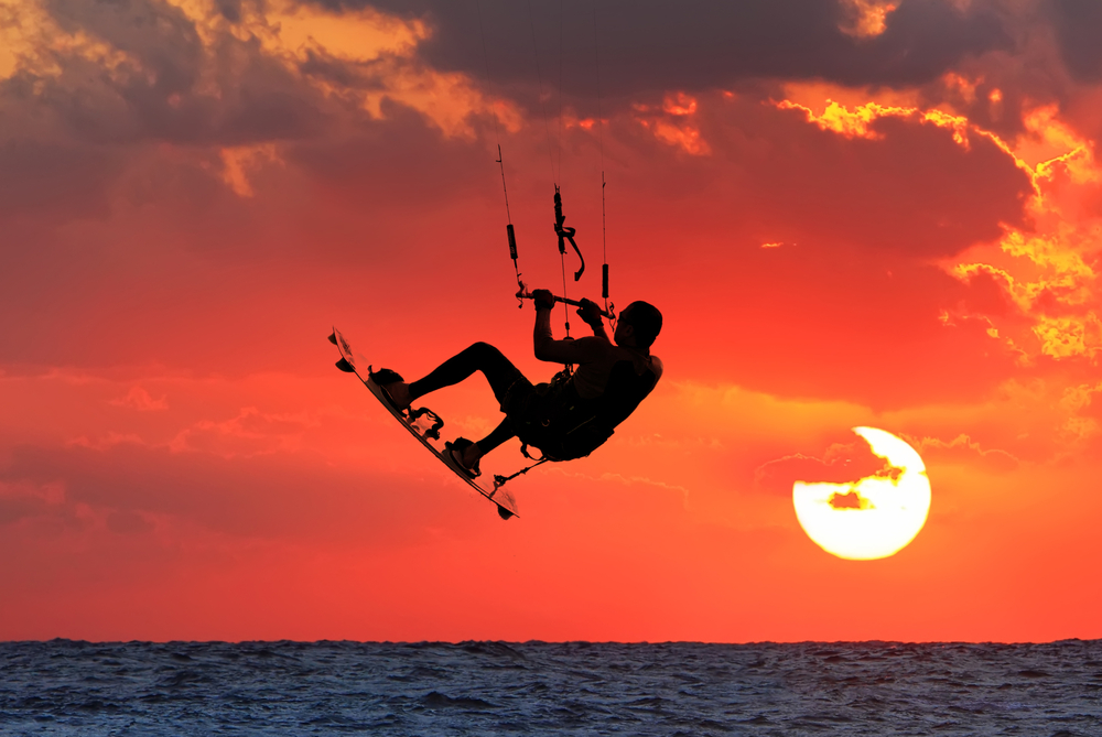 Kitesurfing or Kiteboarding on orange sunset background