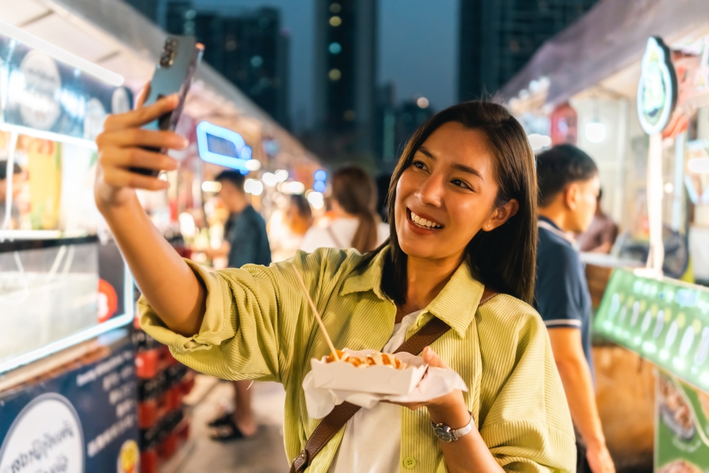 Asian woman enjoy eating fries street food at night market. Traveler Asian blogger women Happy tourists Beautiful female with Traditional thailand bangkok food.