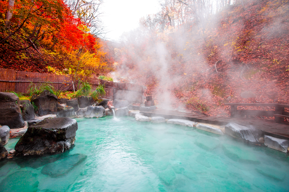 Japanese Hot Springs Onsen Natural Bath Surrounded by red-yellow leaves. In fall leaves fall in Yamagata. Japan.