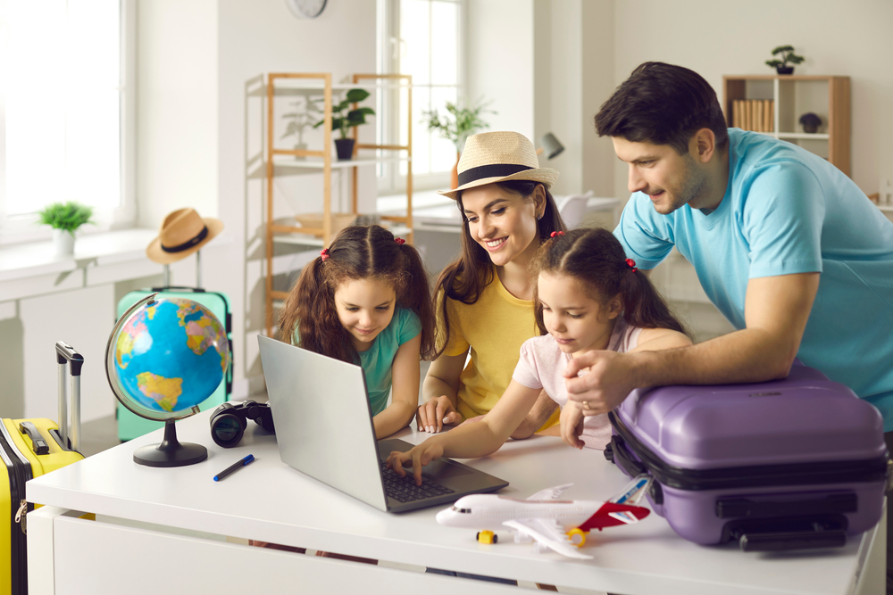 Happy people planning holiday trip. Family getting ready for travel vacation using laptop computer to monitor prices, pick airline, buy tickets, purchase flight, look for rentals or book hotel room