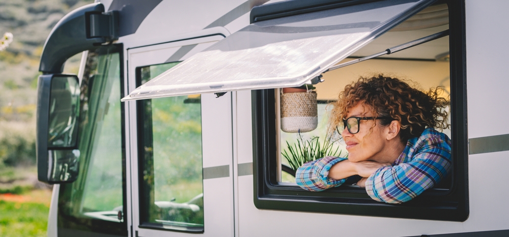 Daydreamer serene and happy female tourist people enjoying trip destination admiring nature outdoor at the camper van window. Living off grid alternative tiny house on wheels. Renting vehicle vacation