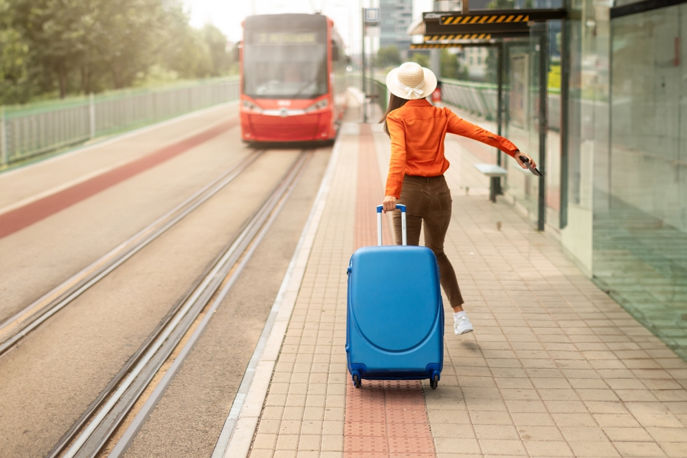 Missed Streetcar. Young woman with suitcase in a rush, running to catch the tram at a bustling city stop, being late. 