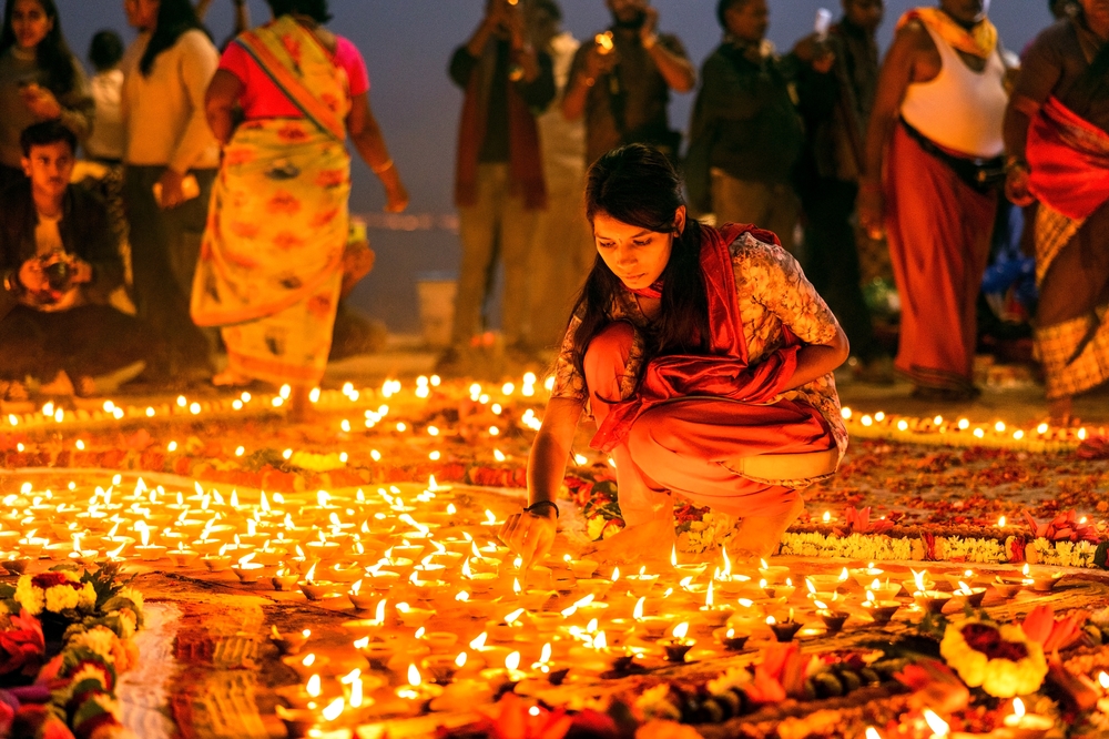 VARANASI, UTTAR PRADESH, INDIA -2023_11_27: Devotees light earthen oil lamps on the occasion of Dev Deepavali. It is the biggest Light Festival, where devotees decorate the river bank Ganga with Lamps