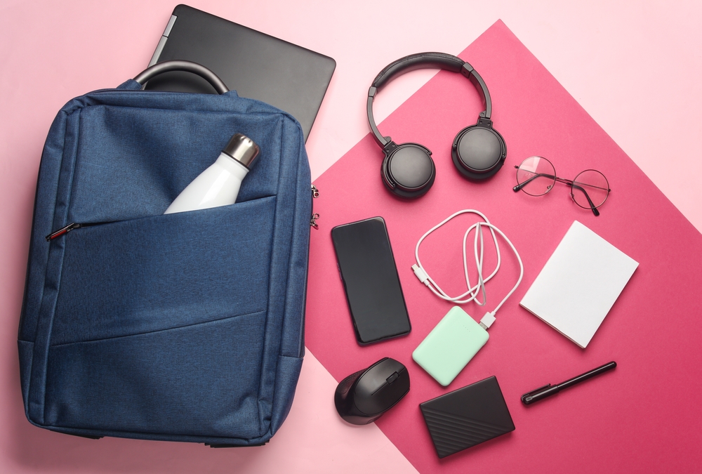 Laptop with Modern gadgets and accessories for work and study in Backpack on pink background.