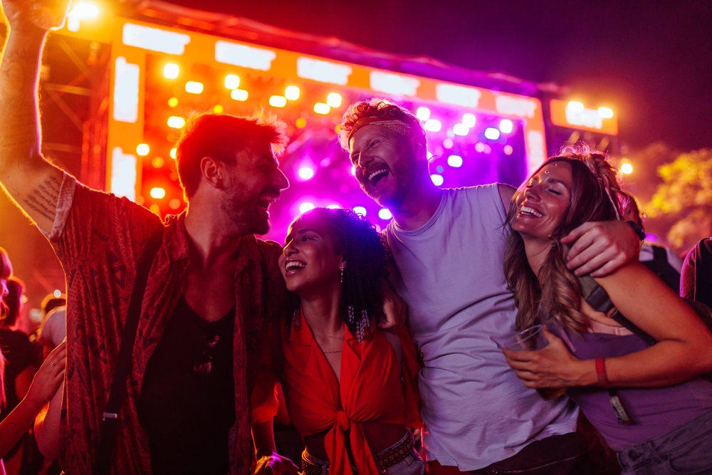 Friends are having fun at a music festival. They are wearing leisure stylish clothes.