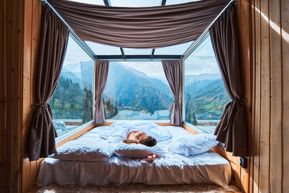 Tranquil serene calm woman sleeping on a soft white cozy comfortable warm bed in room with mountains view