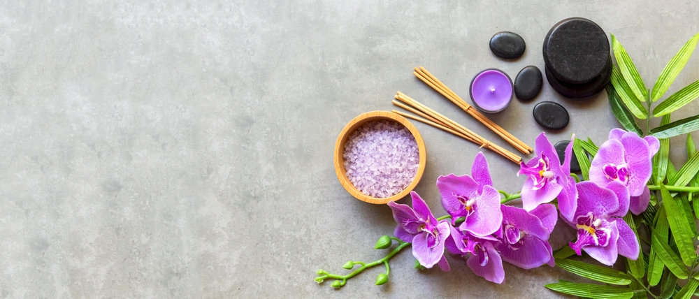 Thai Spa Treatments aroma therapy salt and sugar scrub massage with purple orchid flower on backboard with candle.