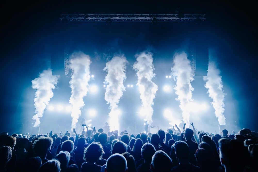 Co2 flame and silhouette of crowd at a music festival in front of bright stage lights