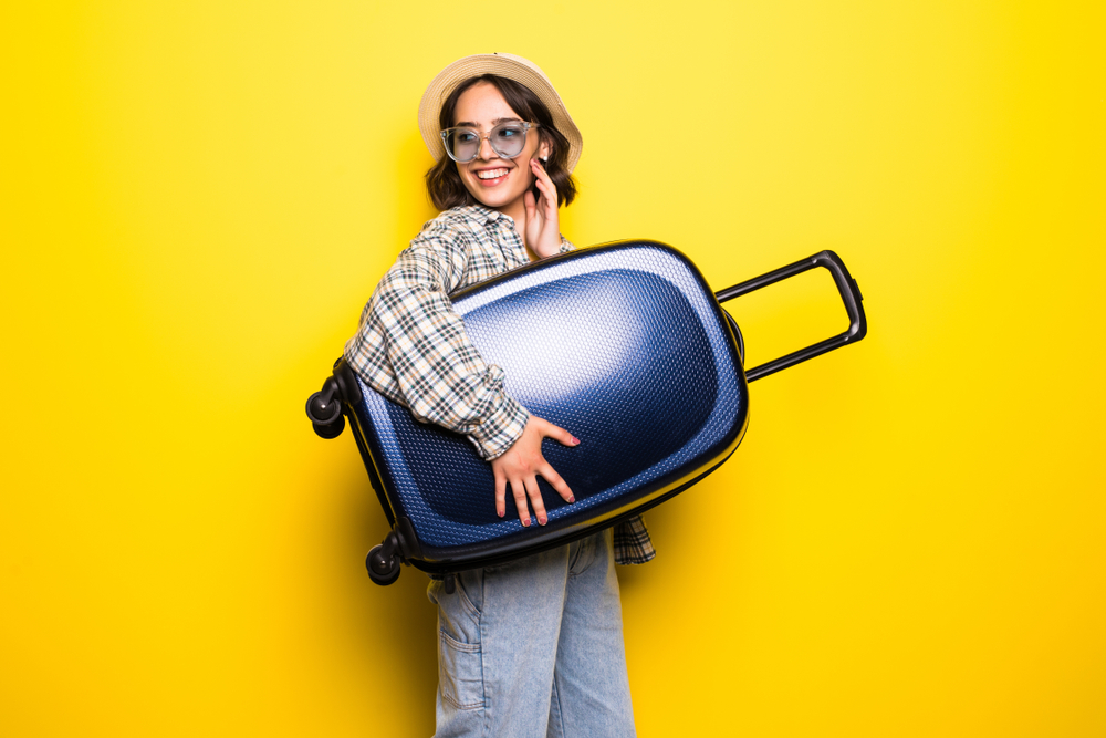 Woman ready for summer travel isolated on yellow background