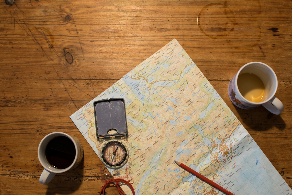 Planning a hiking trip on Lofoten, Norway, using map and compass while drinking coffee.