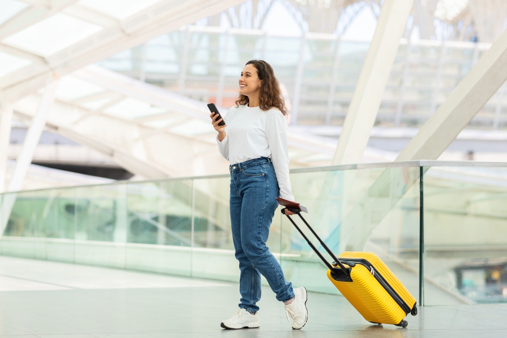 Independent woman traveler using her smartphone while navigating through a modern airport terminal