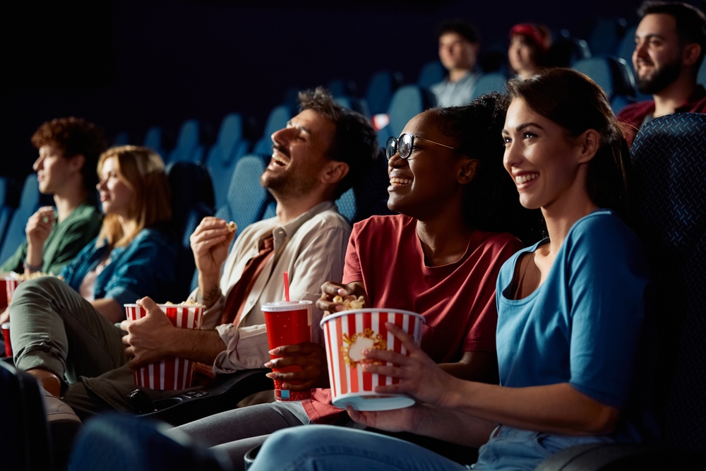 Happy friends enjoying in movie projection in theater.