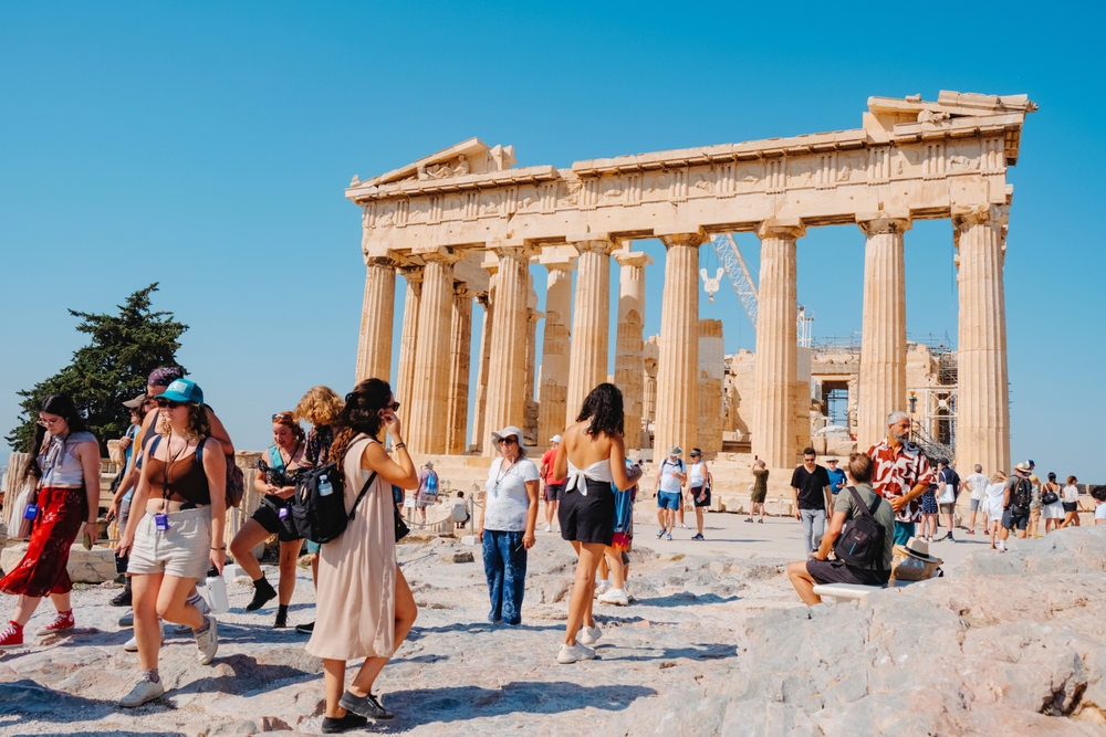 A crowd of visitors by the Acropolis of Athens, Greece, in front of the remains of the famous Parthenon, on a summer day