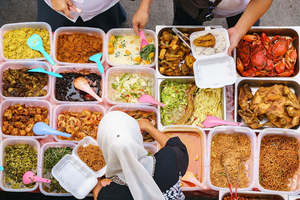 Overhead shot of people buying food over variety of delicious Malaysian home cooked dishes sold at street market stall in Kota Kinabalu Sabah.