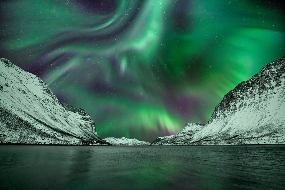 Northern Lights dancing over the fjord with reflection on the sea