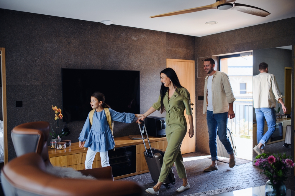 Happy young family with two children enetring room at luxury hotel, summer holiday.