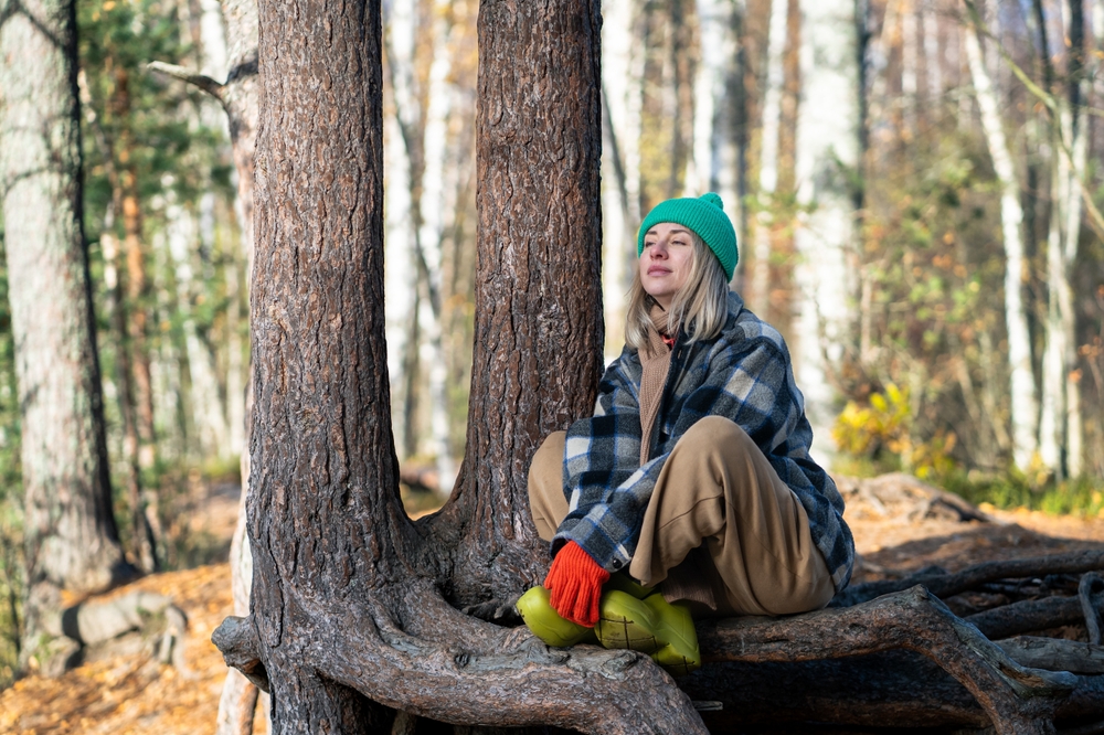 Serene woman basking in autumn sun, enjoying tranquil forest and fresh air. 