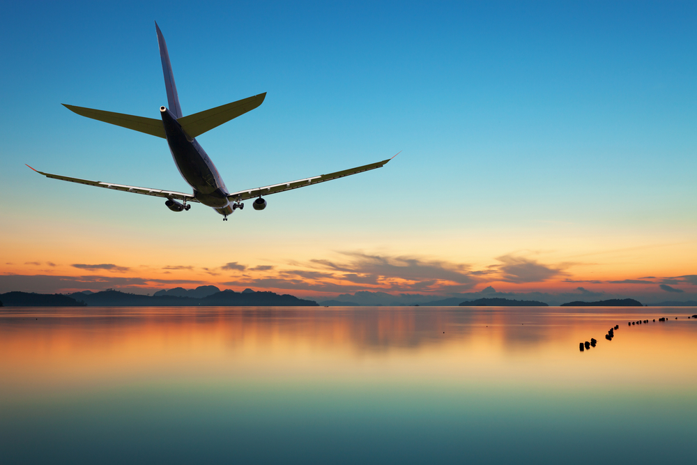 Airplane flying over tropical sea at beautiful sunset or sunrise scenery background,Amazing sea nature landscape background