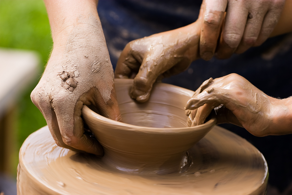 A potters hands guiding a child hands to help him to work with the ceramic wheel See similar photos in my portfolio.